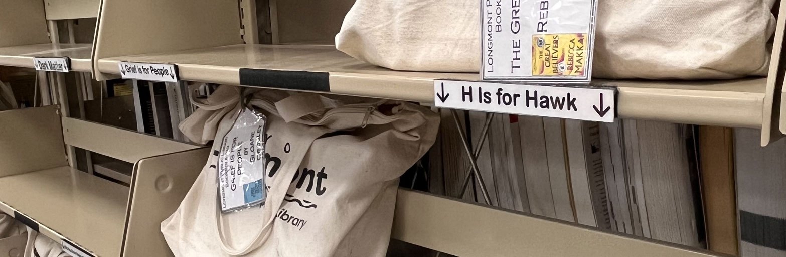 shelf of Library bags holding book club books in a bag kits canvas bags with a black logo and a tag