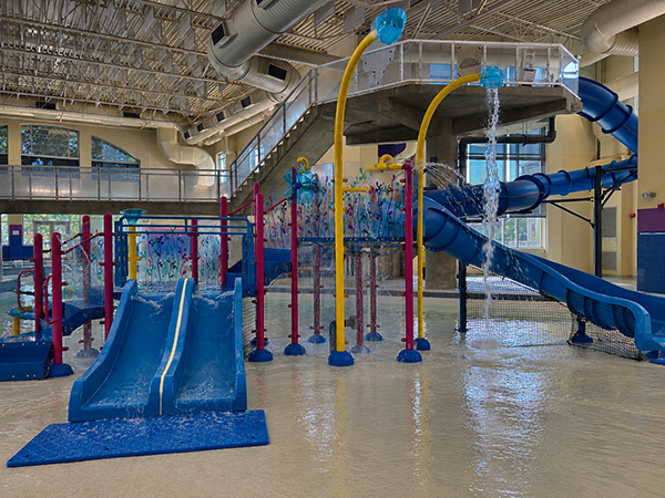 indoor leisure pool play feature including slides and dump buckets in shallow water